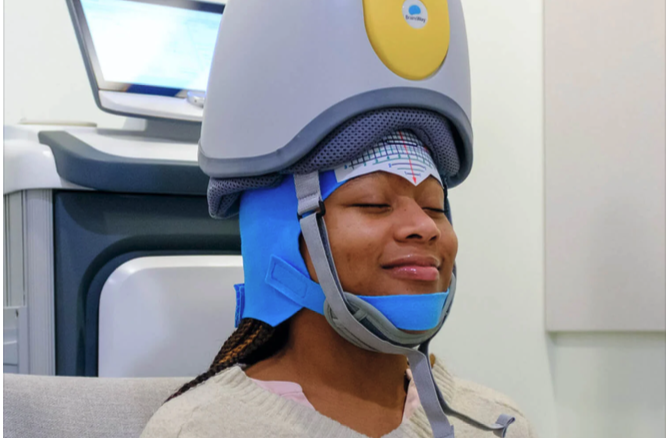 A woman wearing a headpiece of TMS therapy and looking ecstatic